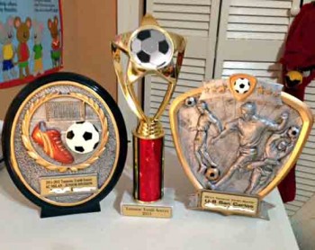 Parent displays their custom trophies on left and right that has their child's name and in the middle, the generic on that is given out by the City of Tamarac